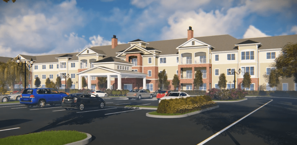 A modern residential building with a parking lot and landscaped area under a blue sky.