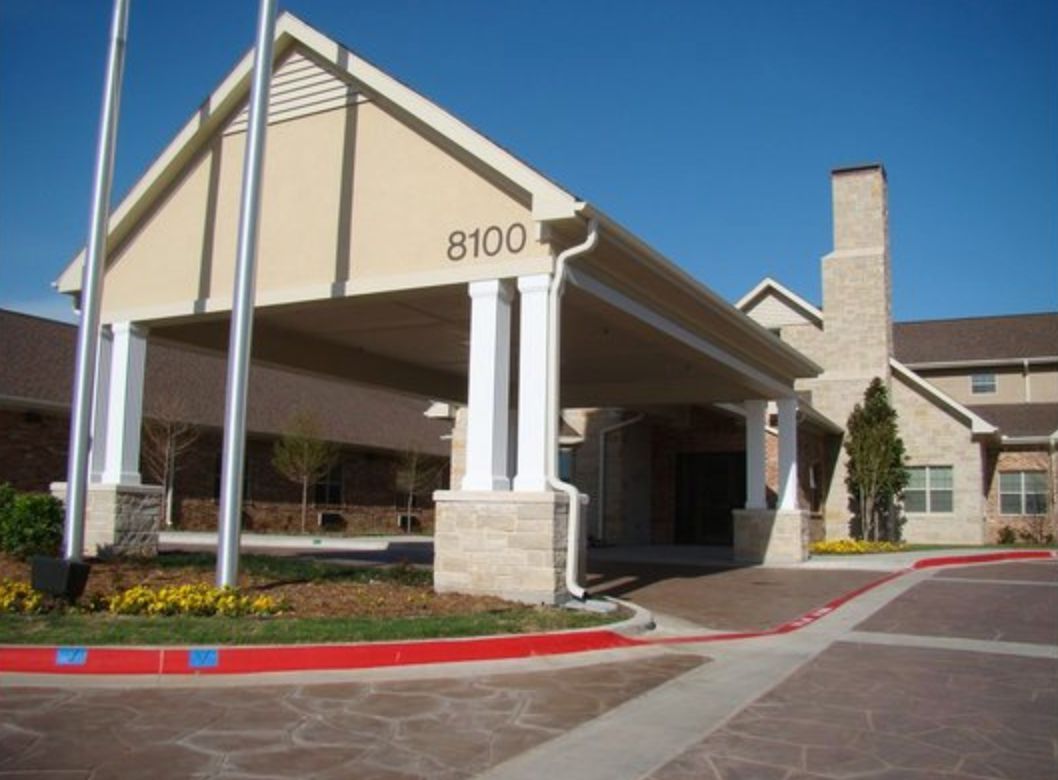 A building with a covered entrance, featuring columns and a driveway.