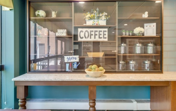 A cozy coffee station with decorative shelves, a 'COFFEE' sign, and a bowl of apples.