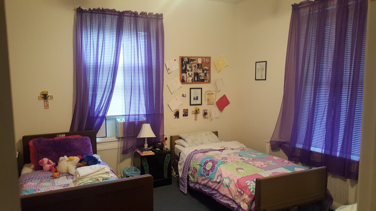 A cozy shared bedroom with purple curtains and twin beds featuring colorful bedding.