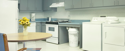 A modern kitchen featuring a stove, refrigerator, and sink with gray cabinetry.
