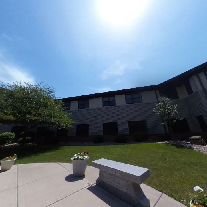 A peaceful courtyard with a bench under a bright, sunny sky.