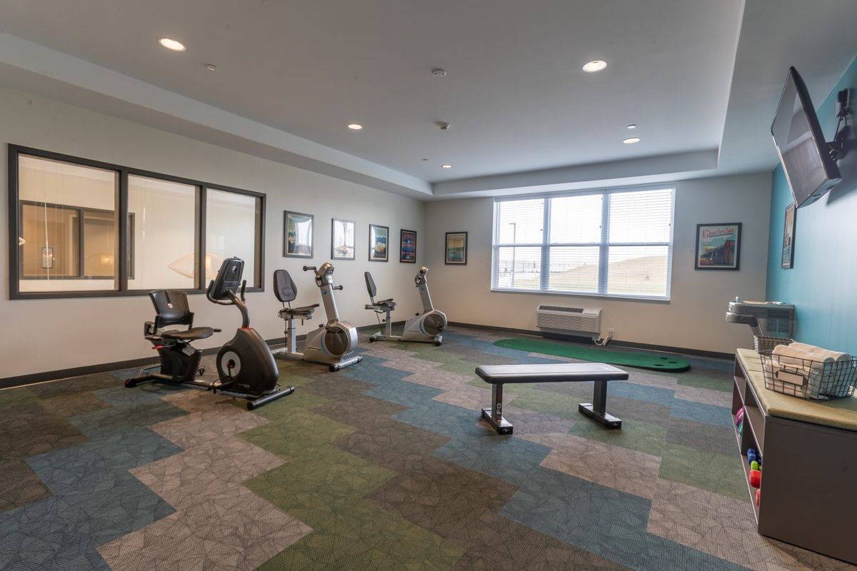 A gym room with stationary bikes and a workout bench.