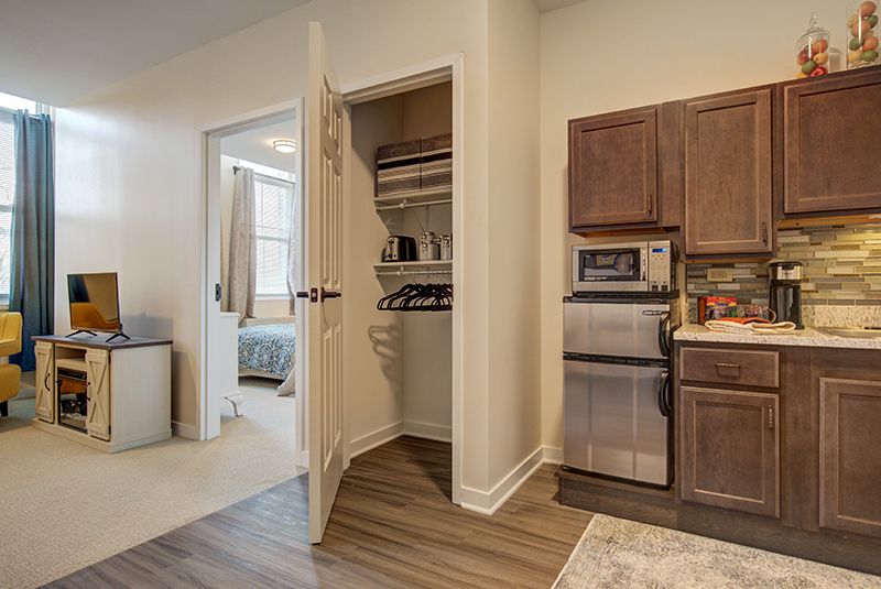 A modern kitchen with an adjoining bedroom and an open closet door.