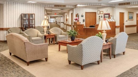 A comfortable lobby area with chairs and sofas, featuring a reception desk in the background.