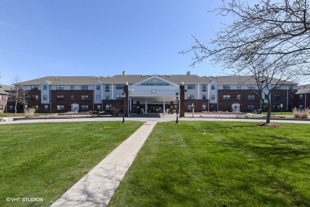 A large building with a central entrance and a well-maintained lawn in front.