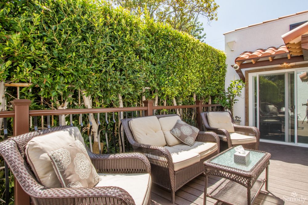 A cozy outdoor patio with wicker furniture and lush greenery.