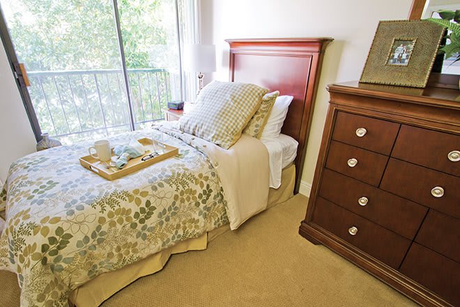 A cozy bedroom with a neatly made bed and wooden furniture.