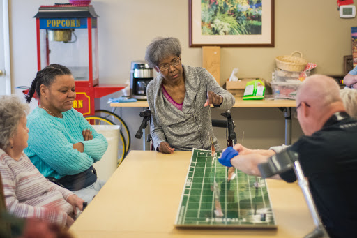 Elderly individuals engaged in a tabletop game while discussing strategies.