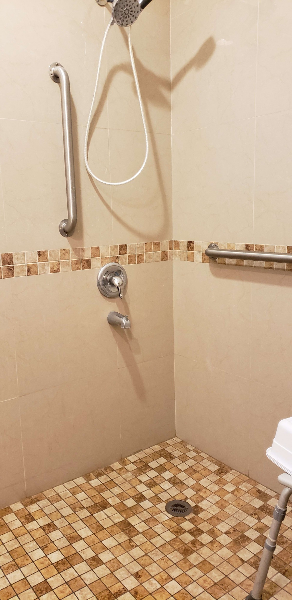 A shower with tiled walls and grab bars installed.