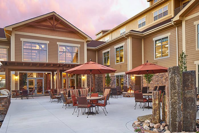An inviting patio area with tables and umbrellas in front of a residential-style building.