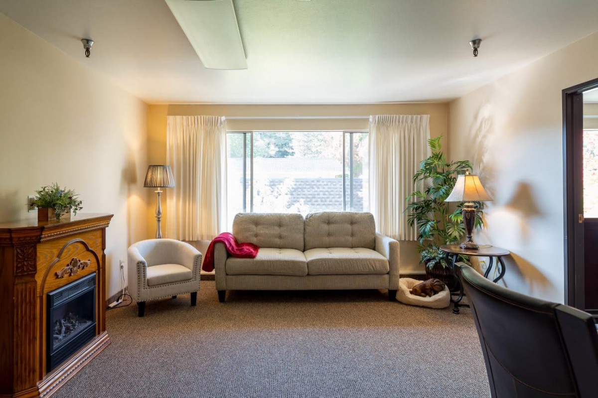 A cozy living room with a sofa, armchair, and large window.
