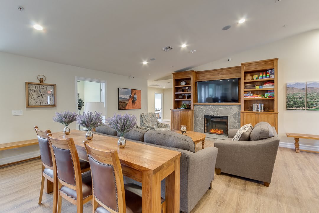 A modern living room with a cozy dining area, featuring a fireplace and built-in shelving.