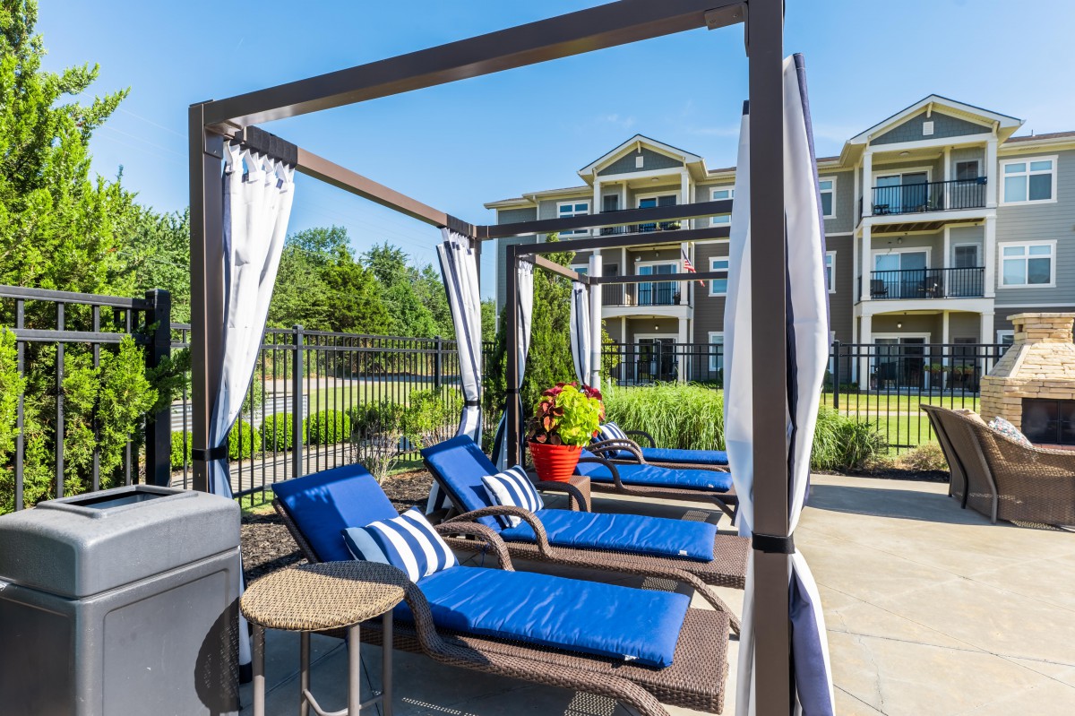 Outdoor poolside area with blue lounge chairs and a cabana.