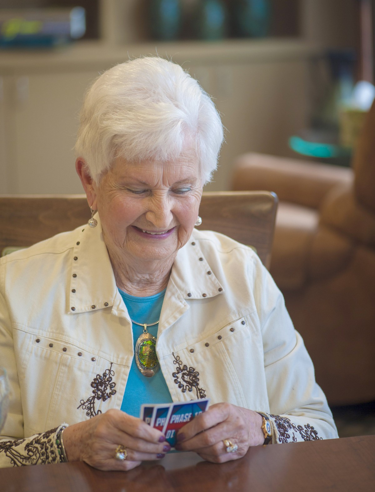 An elderly woman enjoying a game of cards indoors.