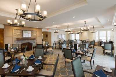An elegant dining room interior with chandeliers, set tables, and comfortable seating.