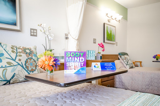 A cozy hospital room designed to promote well-being with floral arrangements and wellness signage.