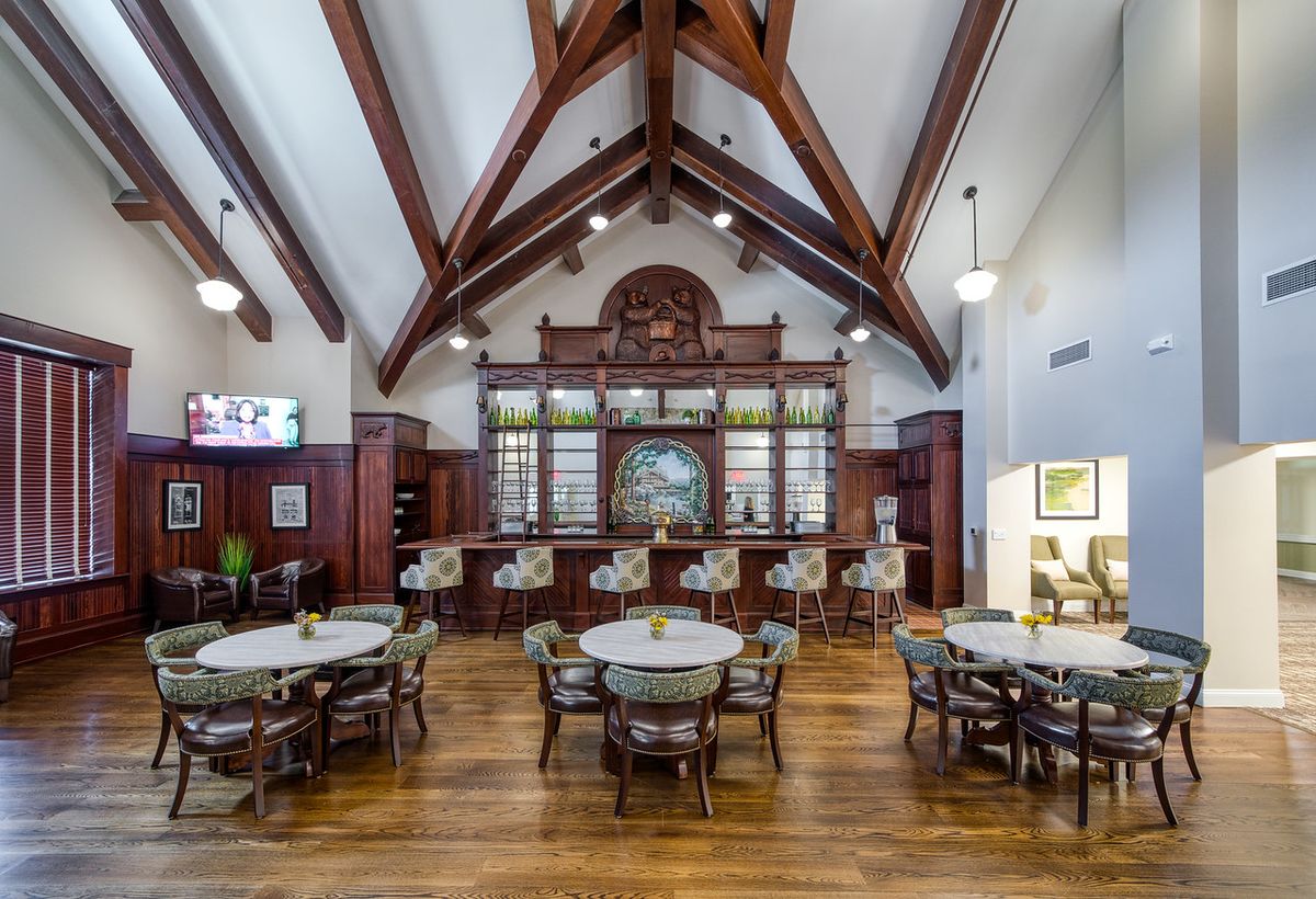 An elegant restaurant interior featuring a bar with wooden beams and stylish decor.