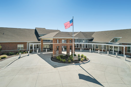 The entrance of a well-designed building with an American flag waving in front.
