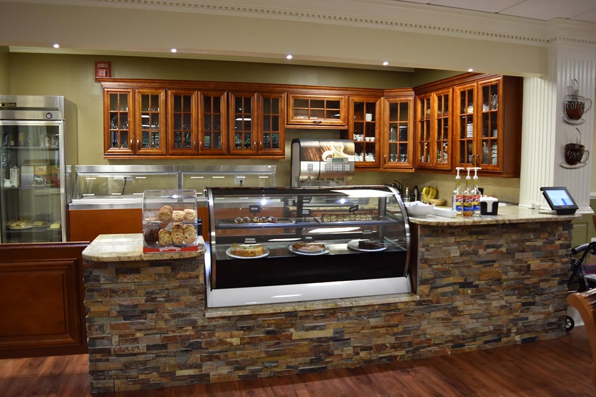 A cozy cafe with a stone facade counter and a display case filled with pastries.