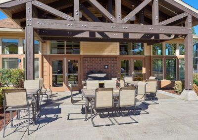An outdoor patio area with tables and chairs set under a wooden pergola.