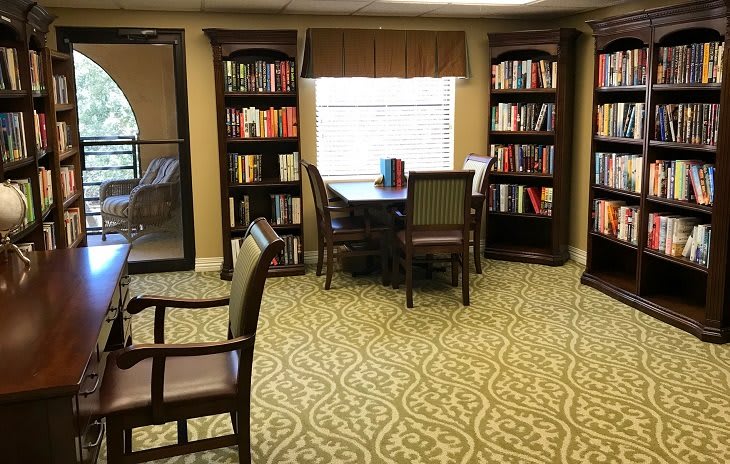 A cozy library corner with bookshelves, a table, and chairs for reading.
