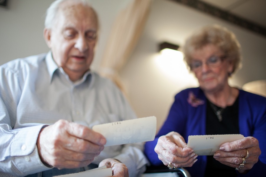 An elderly couple reading together indoors, sharing memories.