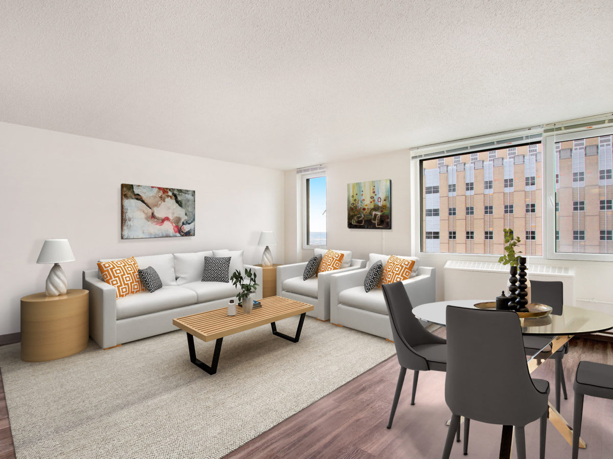 A modern living room with plush sofas, a wooden coffee table, and a dining area overlooking a cityscape through large windows.