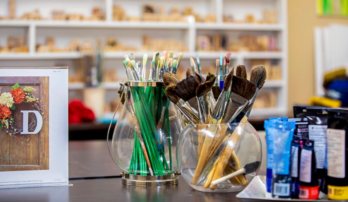 A collection of paintbrushes and pencils in jars on a workspace table in an art studio.