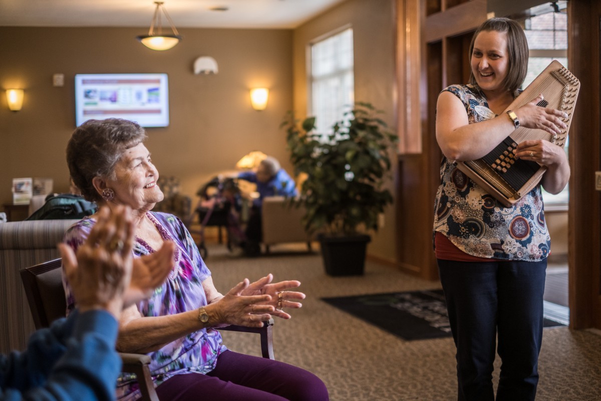 A lively interaction in a community center, with seniors engaging in activities and clapping.