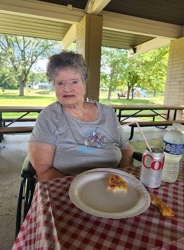 A woman enjoying a meal outdoors at a picnic table.