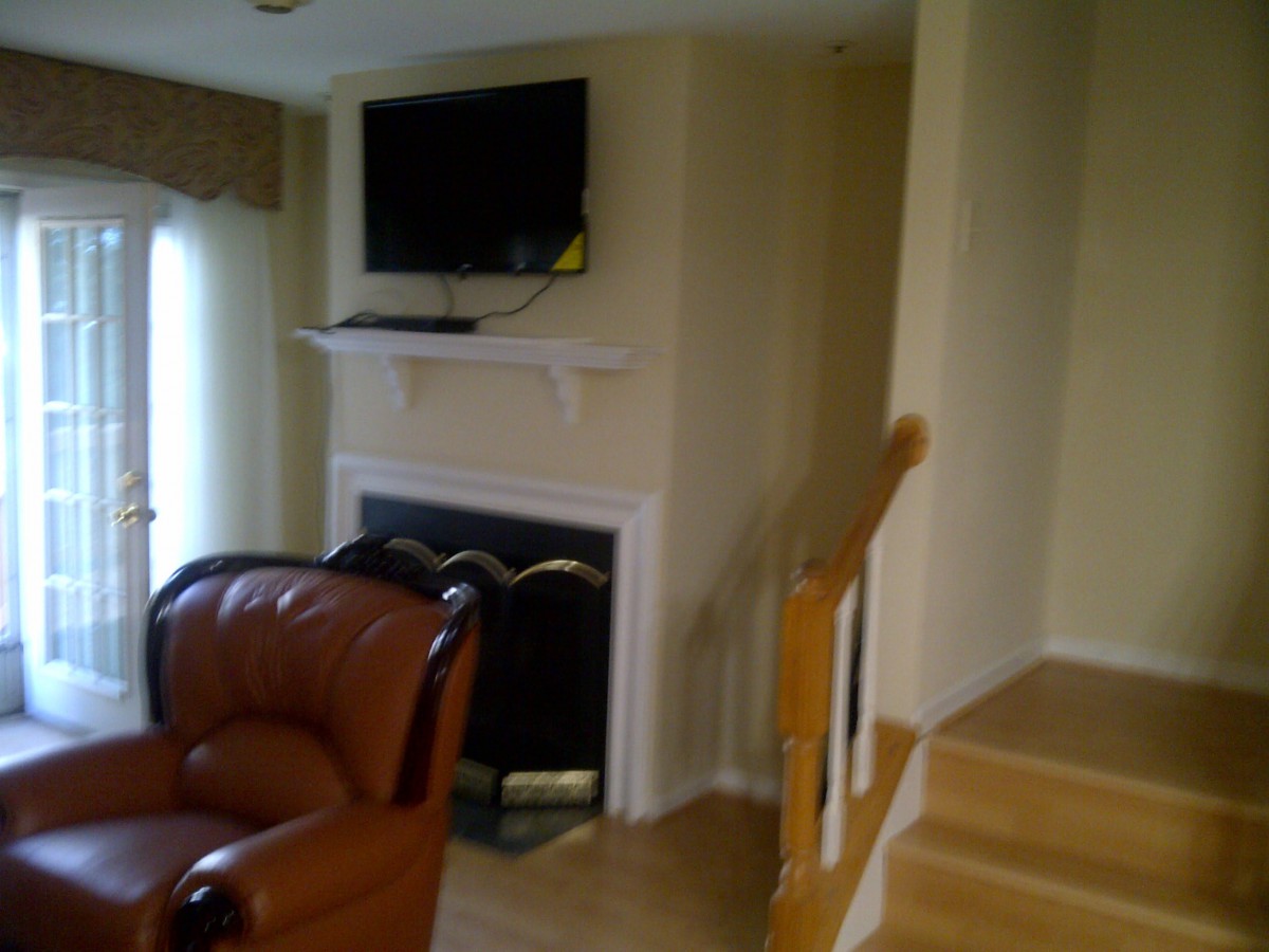 A cozy living room with a fireplace, wall-mounted television, and nearby stairs.