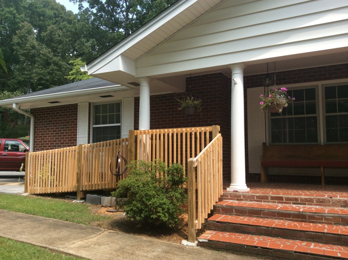 A brick house with a wooden accessibility ramp and porch.