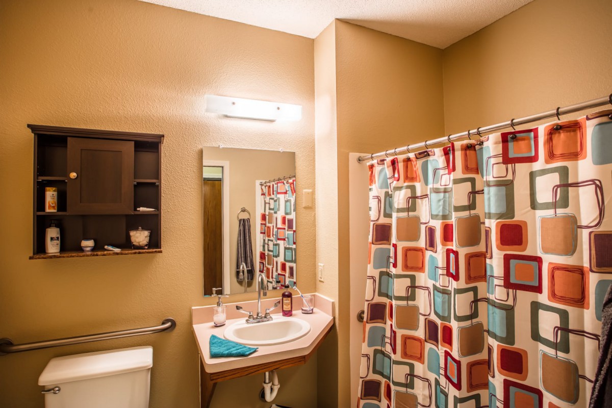 A cozy bathroom with a colorful shower curtain, mirror, and sink.