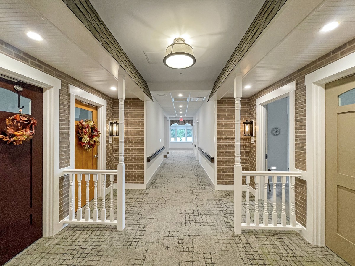 A well-lit hallway with decorated doors and carpeted flooring.