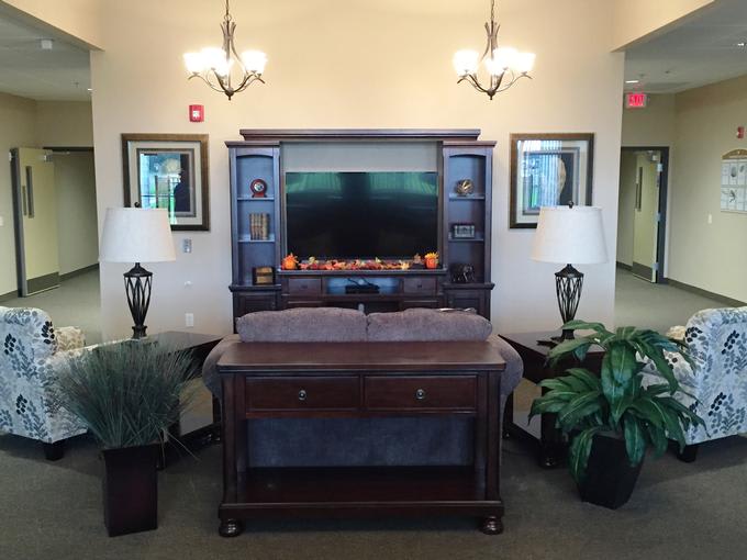 A traditionally styled room with a wooden entertainment center, featuring a television, lamps, and potted plants.