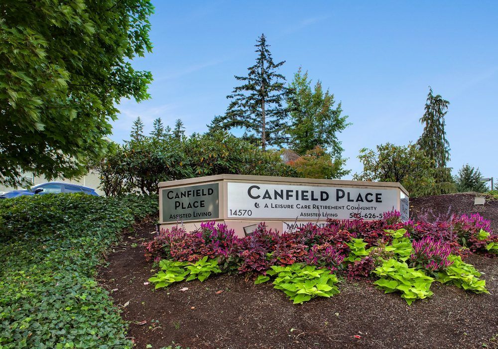 Entrance sign to Canfield Place surrounded by vibrant landscaping and greenery.