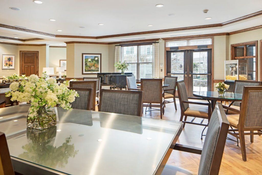 A well-lit dining area with tables, chairs, and decorative flowers.