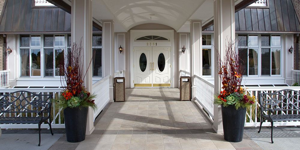 Elegant entrance with double doors and potted plants on either side.