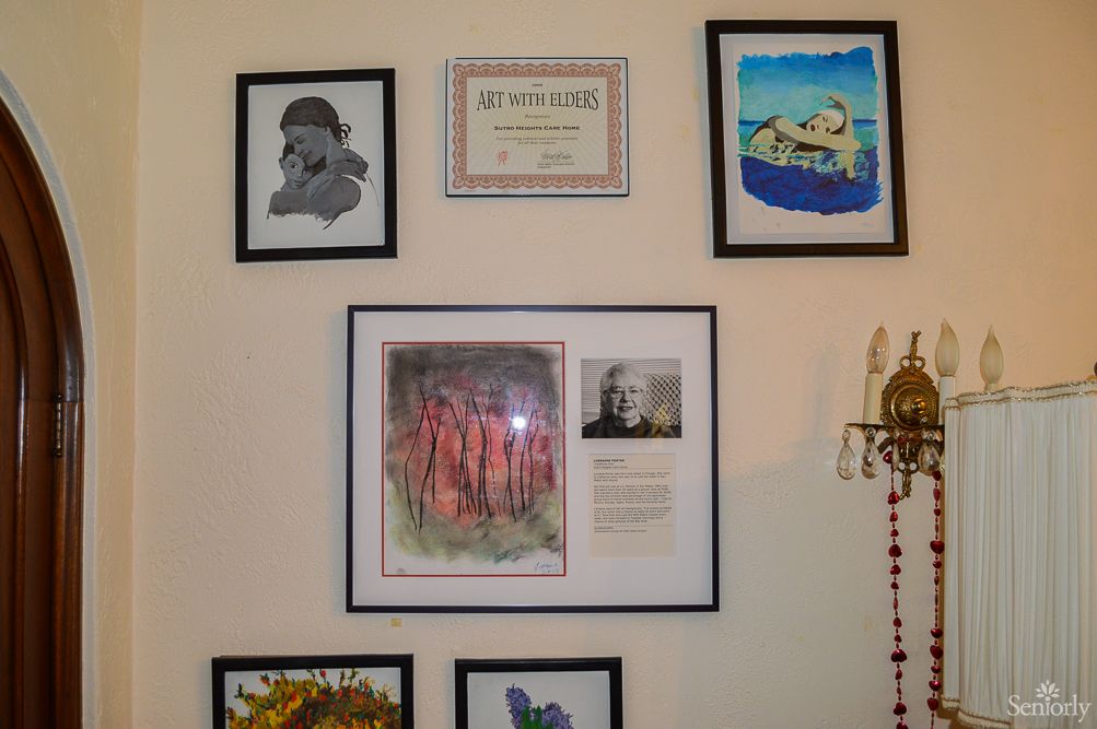 A collection of framed artwork and a certificate displayed on a gallery wall.