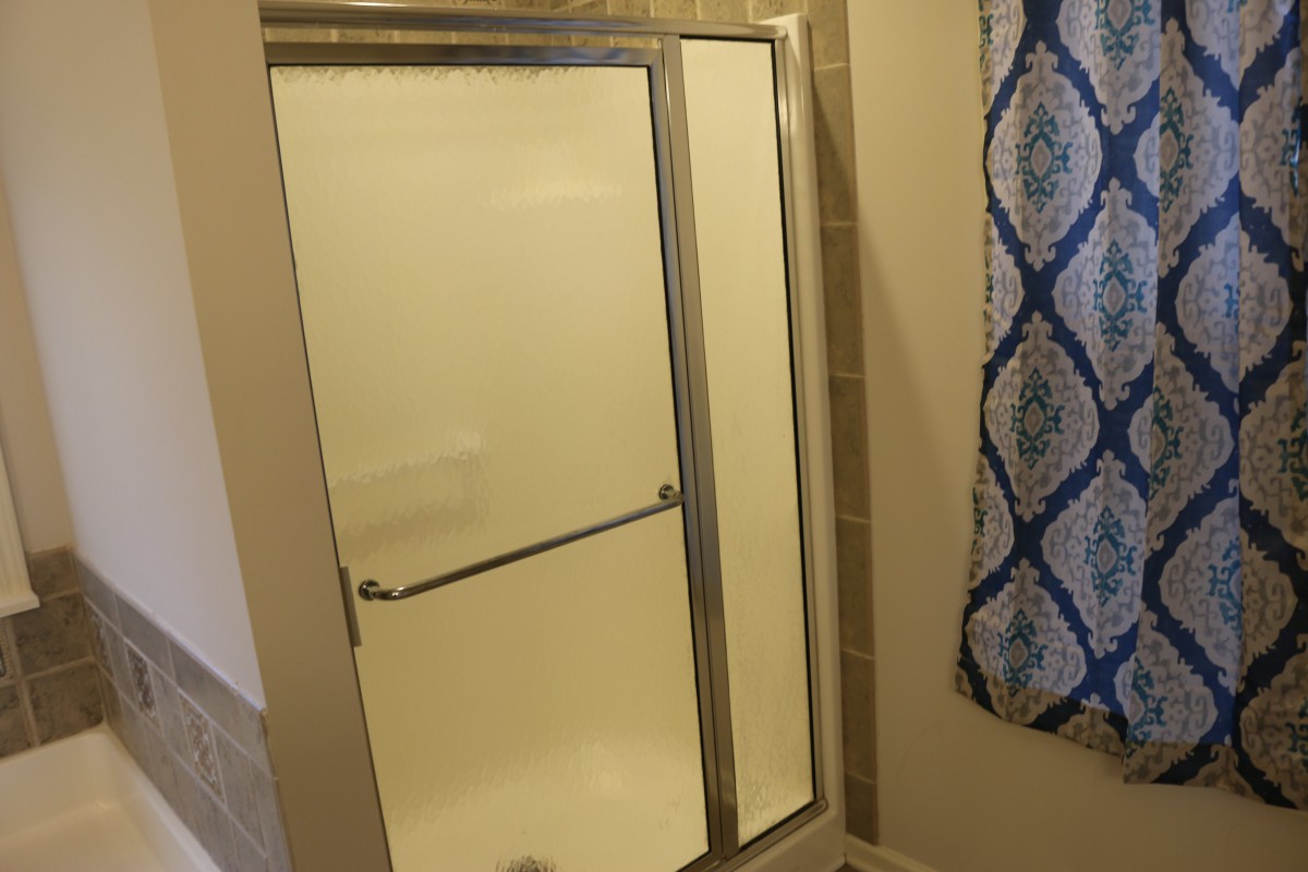 A bathroom featuring a shower with a glass sliding door and tiled walls.
