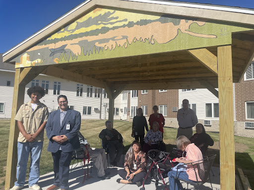 A community gathering under a beautifully painted shelter, showcasing diverse individuals engaged in conversation.