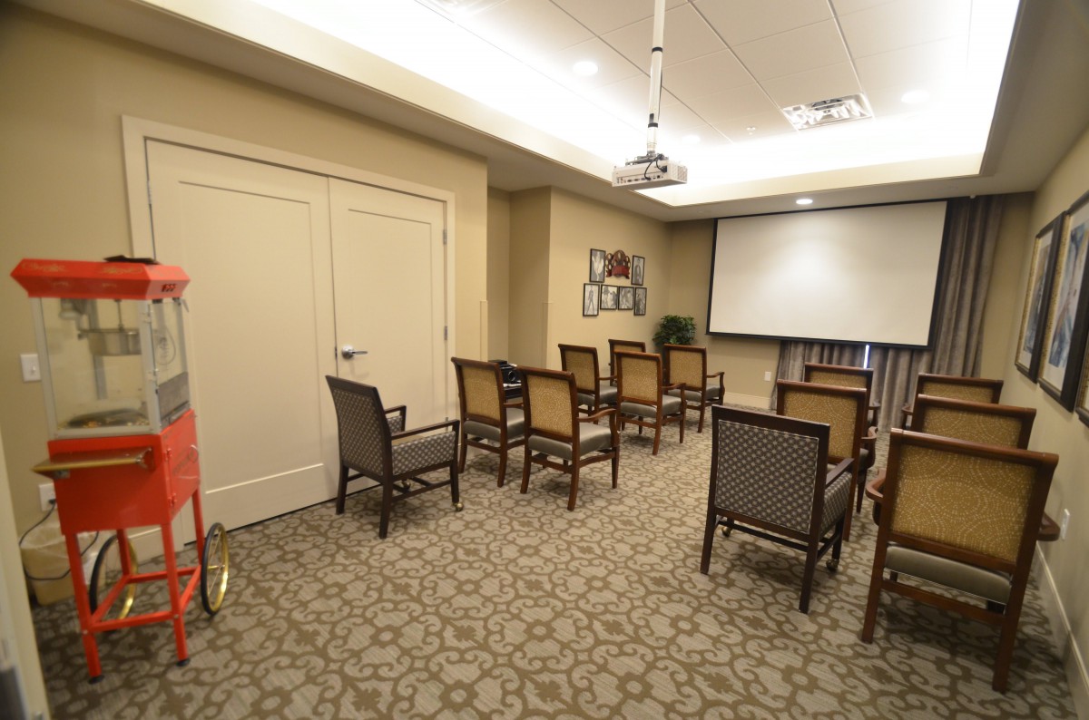 A small conference room with rows of chairs facing a projector screen.