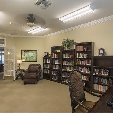 A cozy library with bookshelves, a comfortable chair, and interior lighting.