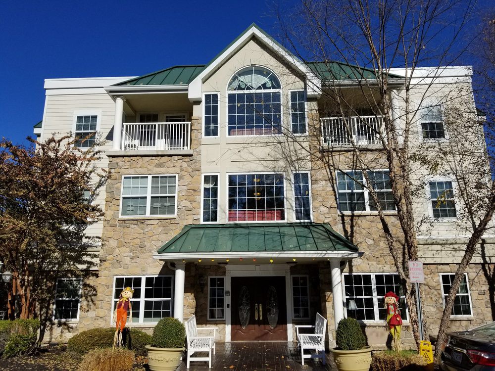 A three-story residential building with a green roof and large windows on a clear day.