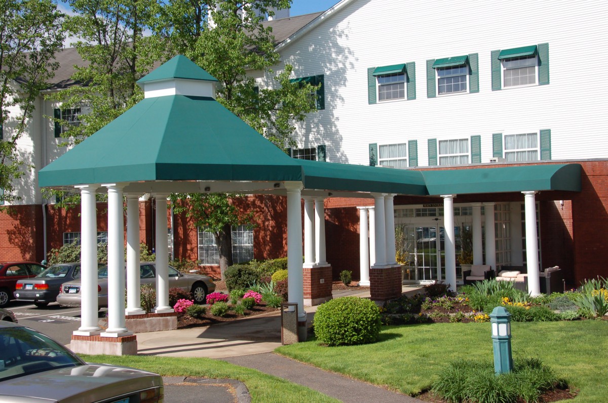 The entrance of a hotel with a green roof and landscaped garden.