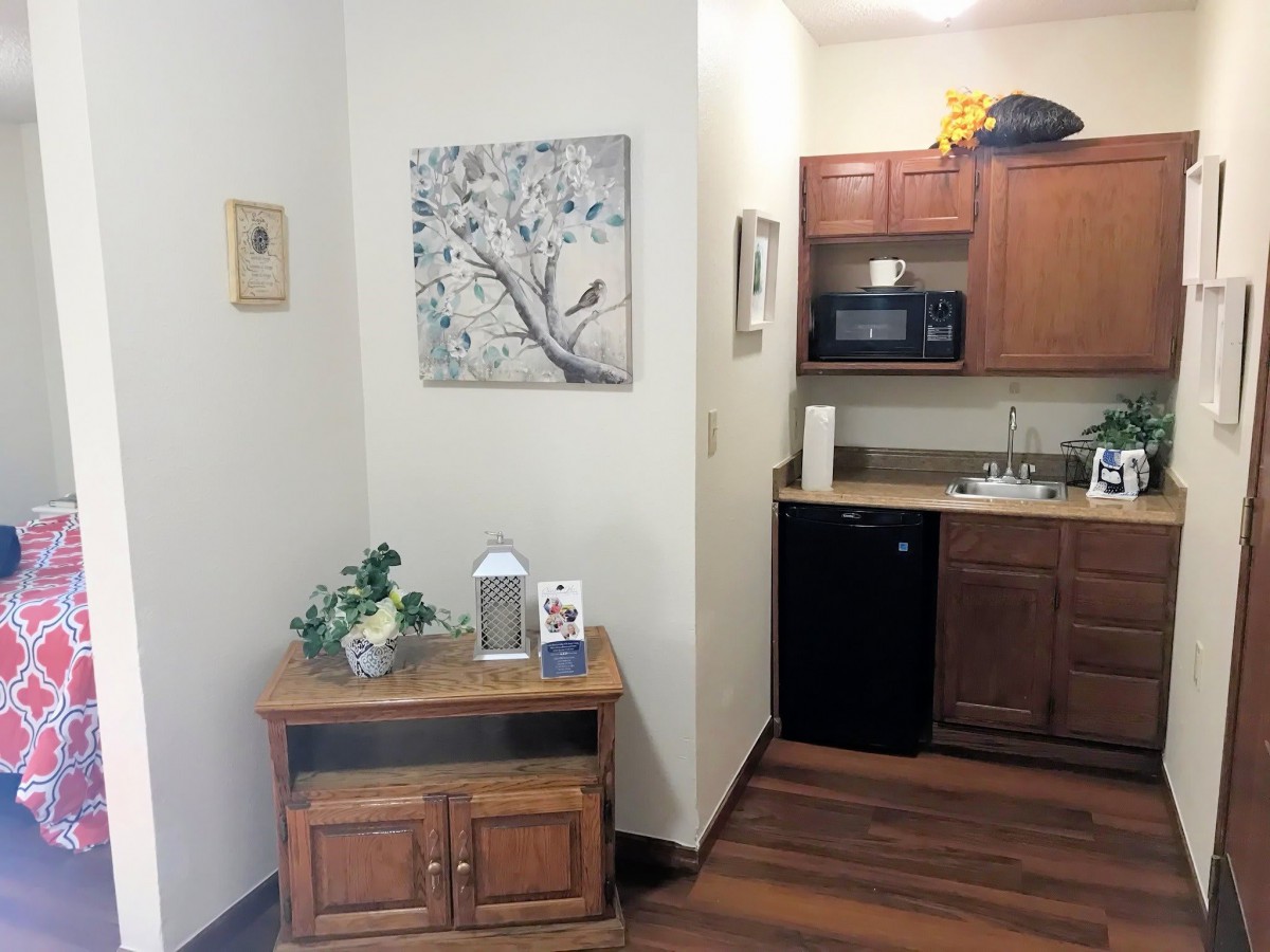 A cozy kitchen corner with a wooden cupboard, decorative items, and a wall painting.