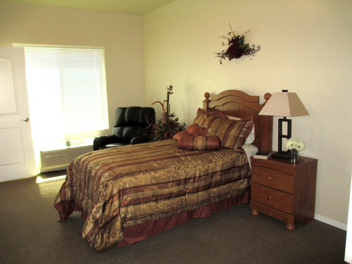 A cozy bedroom with a bed, nightstand, and armchair near the window.