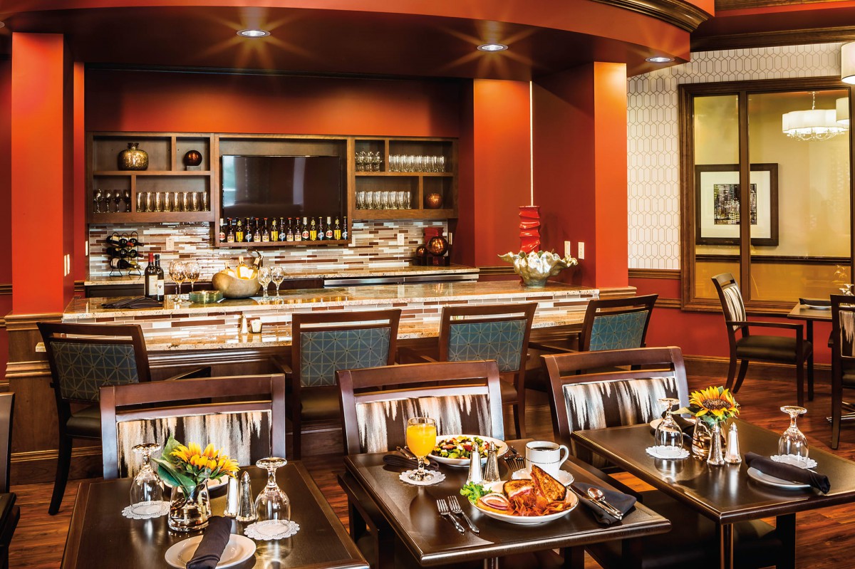 A stylish restaurant interior featuring a well-stocked bar and neatly arranged dining tables.