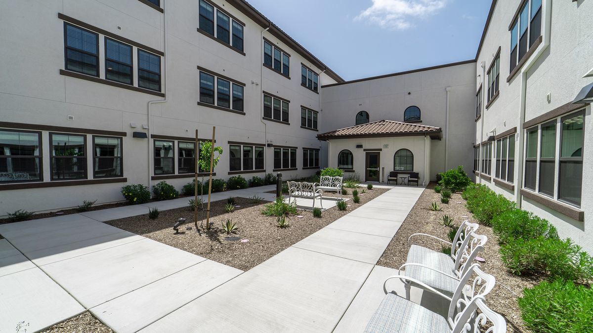 A modern courtyard with benches and pathways surrounded by a multi-story building.
